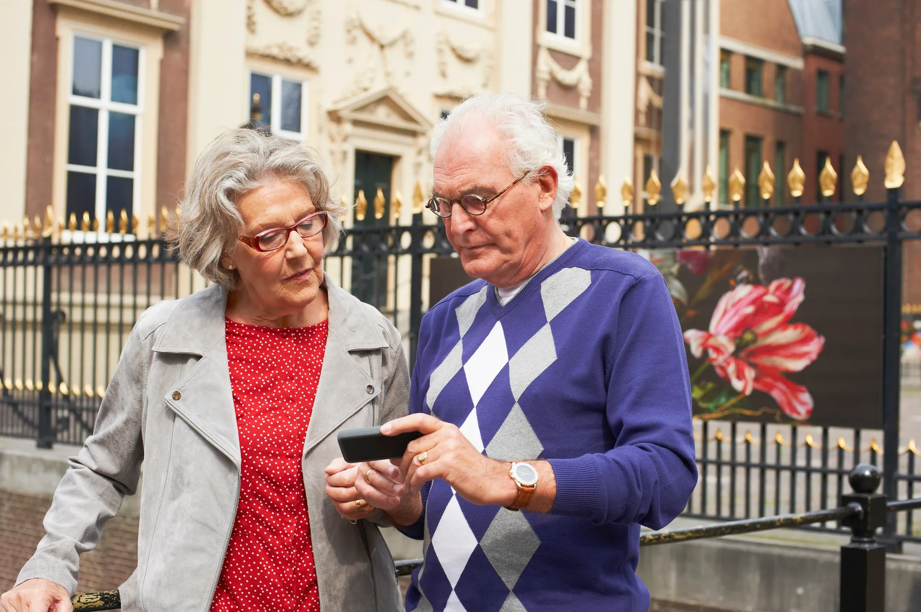 Ouder stel bekijkt samen een telefoon in de stad