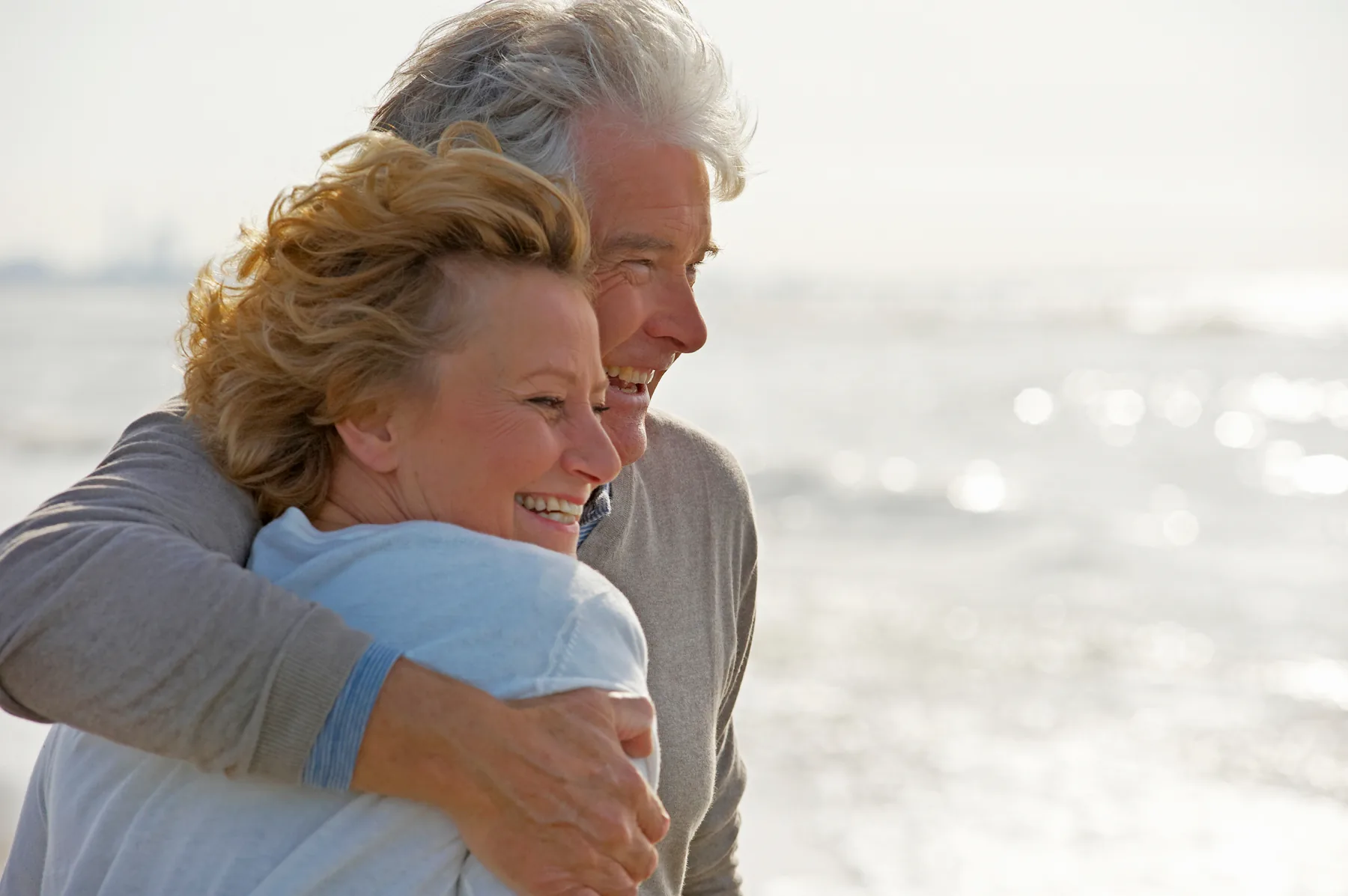 Ouder stel lacht samen aan zee